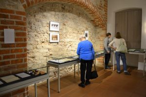 Drei Personen betrachten Exponate der Ausstellung "Andenken"